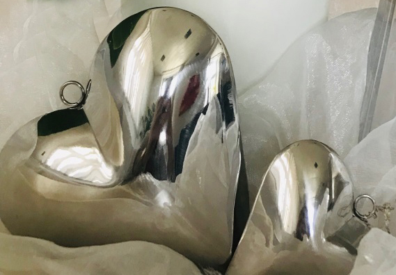 Zwei glänzende Metallherzen in Seidenpapier verpackt